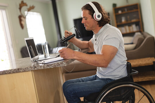 Caucasian disabled man recording podcast using microphone sitting on a wheelchair at home