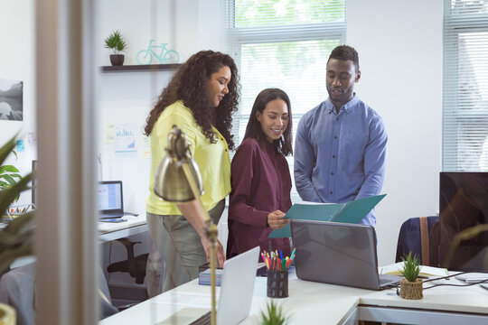 Happy diverse group of business people working together, discussing work in modern office