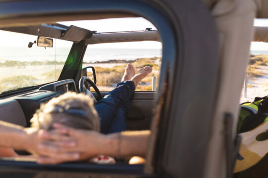 Relaxed caucasian man lying in car, resting at seaside