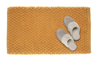 Fototapeta na wymiar Soft orange bath mat and slippers isolated on white, top view