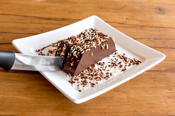 Chocolate pudding with sprinkles, knife cutting piece with delicious chocolate dessert.