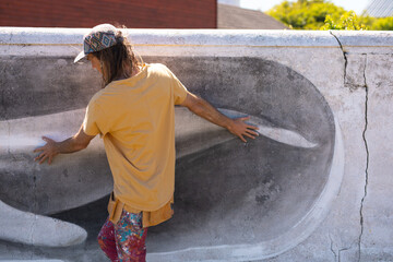 Rear view of male artist walking while touching whale mural painting on wall