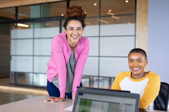 Portrait of smiling multiracial businesswomen in casuals at desk in creative office
