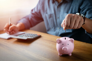 Obraz na płótnie Canvas image of man hand putting coins in pink piggy bank for account save money. Planning step up, saving money for future plan, retirement fund. Business investment-finance accounting concept.