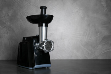 Modern electric meat grinder on black table. Space for text