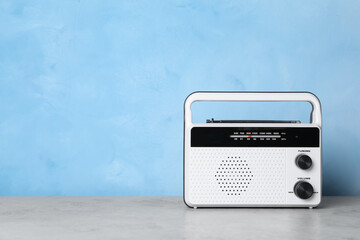 Fototapeta premium Retro radio receiver on grey table against light blue background. Space for text