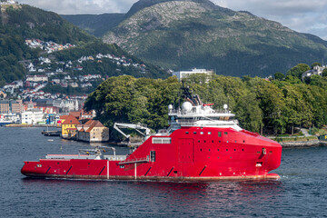 A red multi-purpose vessel in the harbour of Bergen, Norway