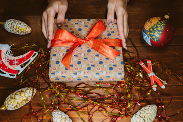 Christmas present in woman's hands. Female hands holding new year gift. New year decoration background