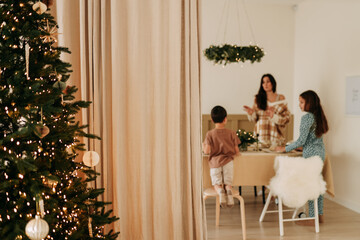 Christmas concept. Children help their mother to set the table. A large family with one parent is preparing for the Christmas holiday in a decorated room during the New Year holidays. Selective focus
