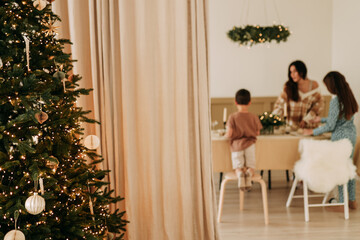 Christmas concept. Children help their mother to set the table. A large family with one parent is preparing for the Christmas holiday in a decorated room during the New Year holidays. Selective focus