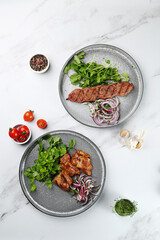 Delicious meat kebab with fresh vegetable. Grilled meat kebabs, vegetables on a marble table