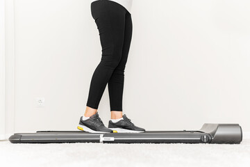 Sporty woman using walking treadmill in the interior of the room or home.