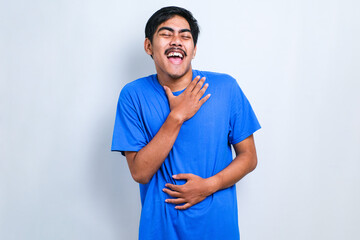 Asian boy smiling and laughing hard out loud because funny crazy joke with hands on body.