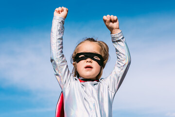 Brave kid in superhero costume showing fists