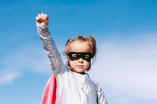 Brave kid in superhero costume showing fists