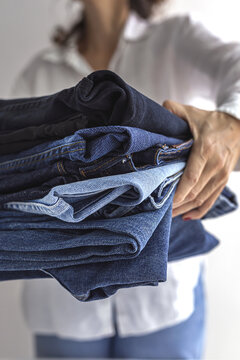 Woman carrying pile of folded jeans