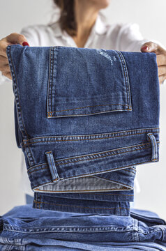Woman folding blue jeans in pile