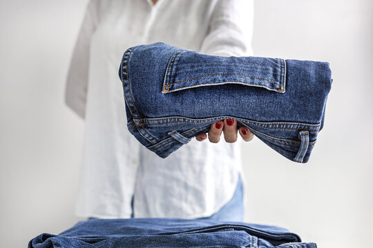 Woman carrying pile of folded jeans