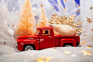 Red small retro toy truck pick up carrying a Christmas tree on the back. Christmas background....