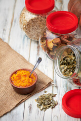 Dry pumpkin seeds in a glass jar on a white wooden board