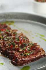 grilled beef chuck steak closeup. sliced steak with chili pepper on ceramic plate
