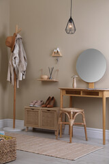 Obraz na płótnie Canvas Modern hallway interior with stylish furniture, round mirror and wooden hanger for keys on beige wall
