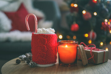 New Year cup with marshmallows, candle and gift on the table on a festive background. Christmas mood