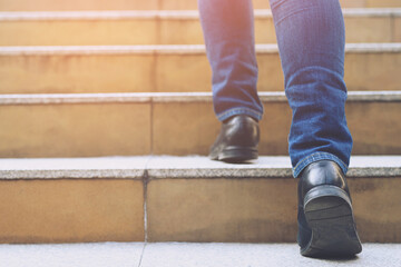 Close up legs shoes of young business man One person walking stepping going up the stairs in modern...