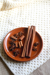 Plate of various winter spices and knitted blanket. Selective focus.