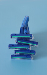 Stack of disposal plastic razors in a light blue background