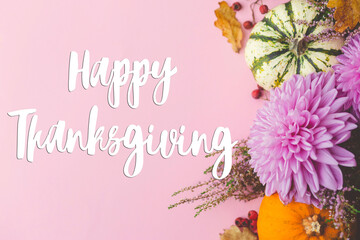 Happy thanksgiving text on pumpkins, dahlias, leaves, heather on pink background flat lay. Seasonal greeting card, handwritten sign. Give thanks