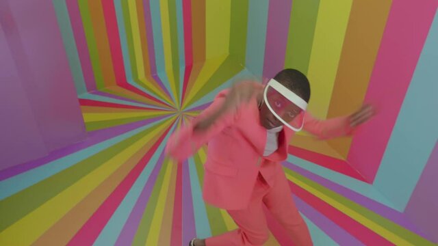 Beautiful young woman dancing and having fun inside a rainbow box room