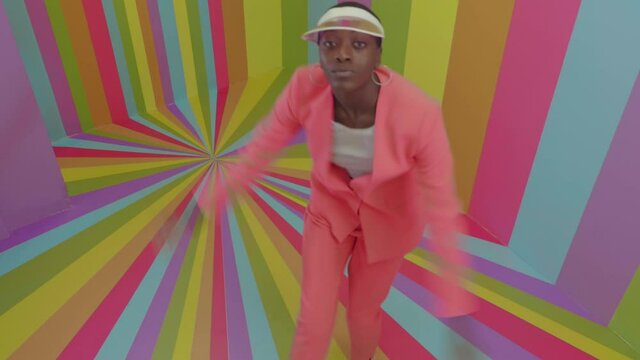 Beautiful young woman dancing and having fun inside a rainbow box room