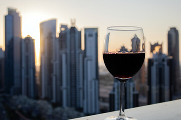 a glass of red wine on the background of the city at sunset