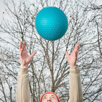 Senior Man (in Late 60s) Is Throwing A Heavy Slam Ball In His Backyard