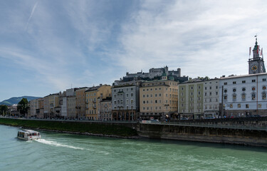 Obraz premium tourist boat cruise on the turquoise Inn river with the historic Old Town and castle of Salzburg in the background