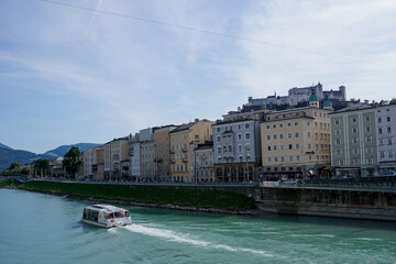 tourist boat cruise on the turquoise Inn river with the historic Old Town and castle of Salzburg in...