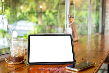 Mockup of digital tablet with empty screen with coffee and smartphone isolate on wooden office desk in coffee shop like the background ,White screen