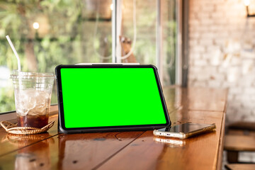 Mockup of digital tablet with empty screen with coffee and smartphone isolate on wooden office desk in coffee shop like the background ,White screen