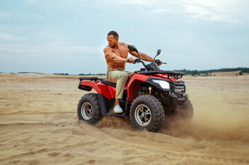 Brutal man poses on atv in desert sands, quadbike © Nomad_Soul
