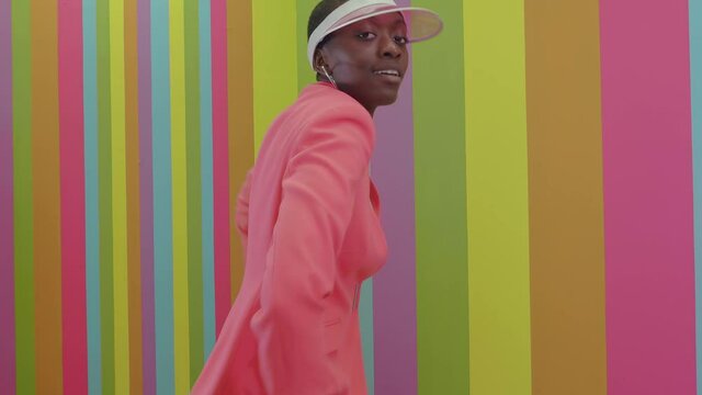 Beautiful young woman dancing and having fun inside a rainbow box room