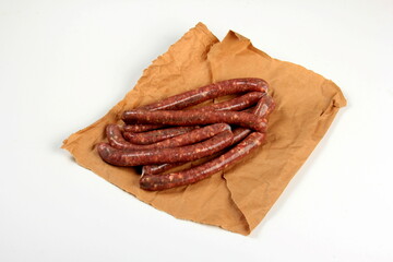 Freshly home made raw breed butchers sausages in skins with spices on cooking paper. Raw beef sausages
