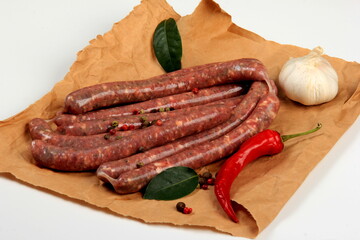 Freshly home made raw breed butchers sausages in skins with spices on cooking paper. Raw beef sausages