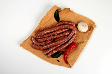 Freshly home made raw breed butchers sausages in skins with spices on cooking paper. Raw beef sausages