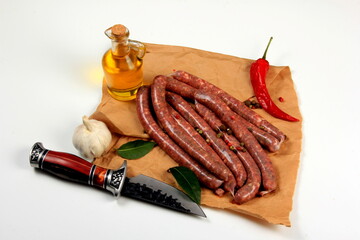 Freshly home made raw breed butchers sausages in skins with spices on cooking paper. Raw beef sausages