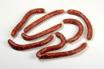 Obraz premium Raw sausage with basil leaf isolated on white background.