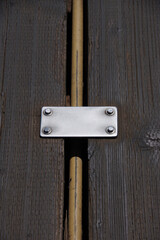 Strong metal plate held by screws designed to protect a supply line between the heavy planks on a public ocean pier