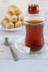 Delight baklava and a glass of tea on a wooden table.