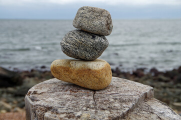 Three stacked stones with sea shore background. Concept of stability.