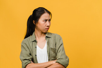 Portrait of young Asia lady with negative expression, excited screaming, crying emotional angry in casual clothing isolated on yellow background with blank copy space. Facial expression concept.